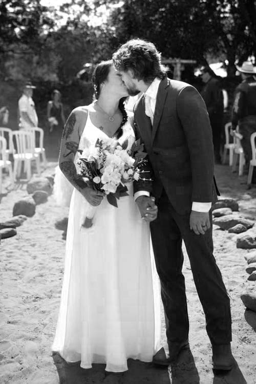 a young bride and groom kissing at their outdoor wedding